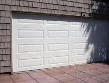 A white garage door sitting on top of a brick floor.