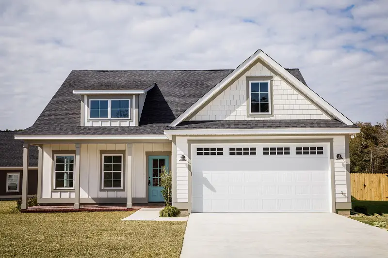 A white house with a blue door and garage.