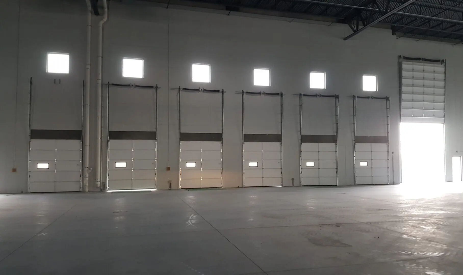 A warehouse with several doors open and windows closed.