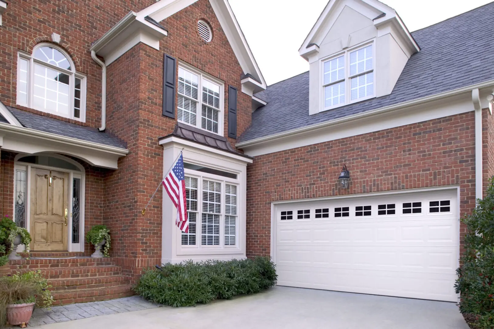 A large brick house with american flag hanging from the side.