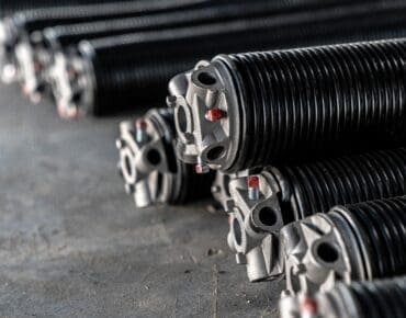 Close-up of heavy-duty commercial torsion springs prepared for industrial garage door installation